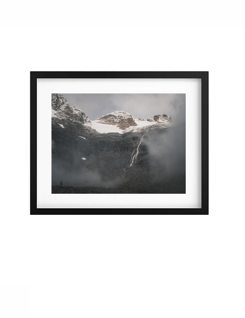 Black-framed Cascade print with a white mat, showing an alpine waterfall beneath snowy peaks.