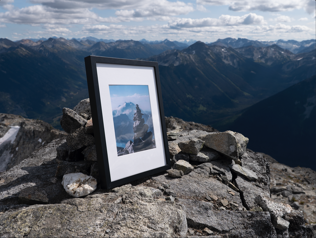 Black-framed Heights print on a rocky ridge overlooking mountains.