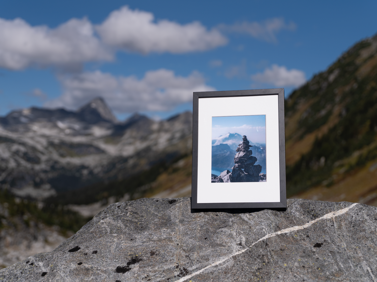 Front view of the black-framed Heights print resting on an alpine rock.