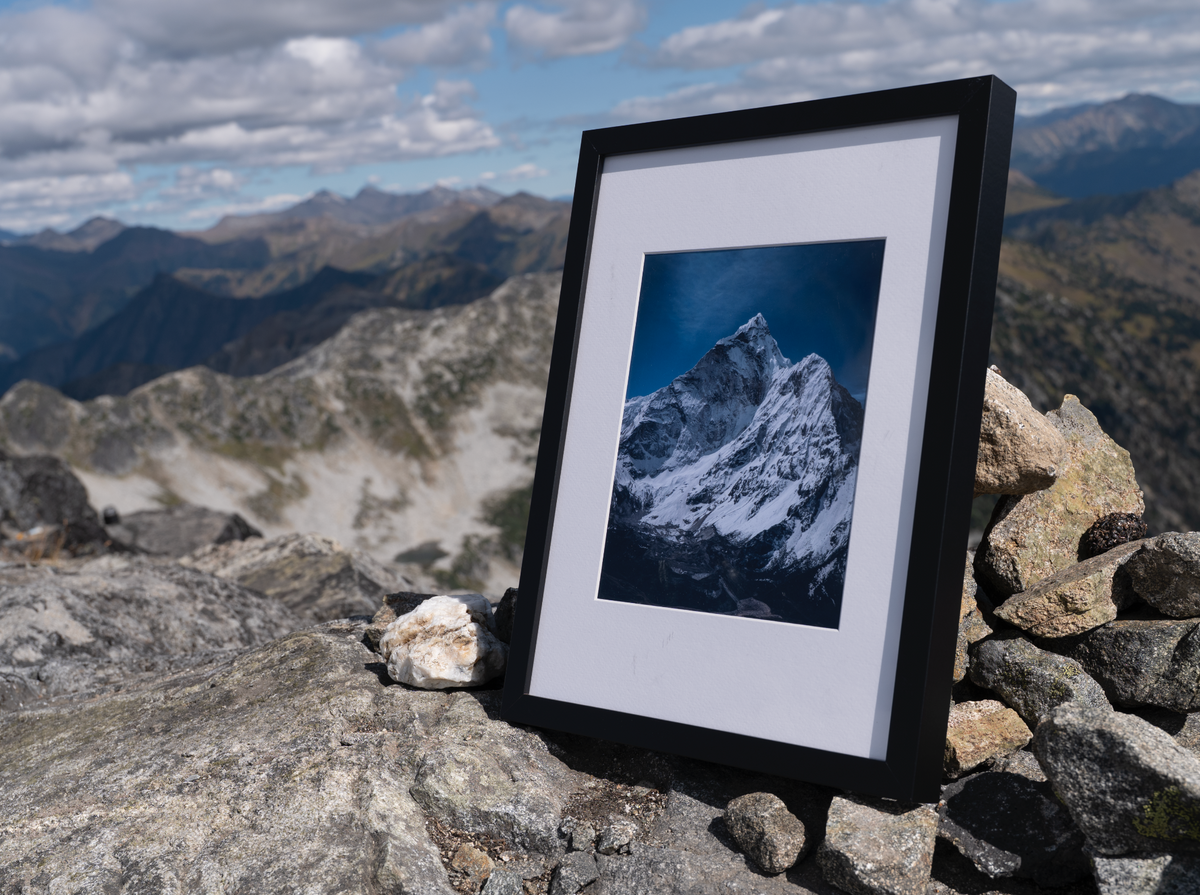 Black-framed Solitude print on a rocky ridge overlooking distant mountains.