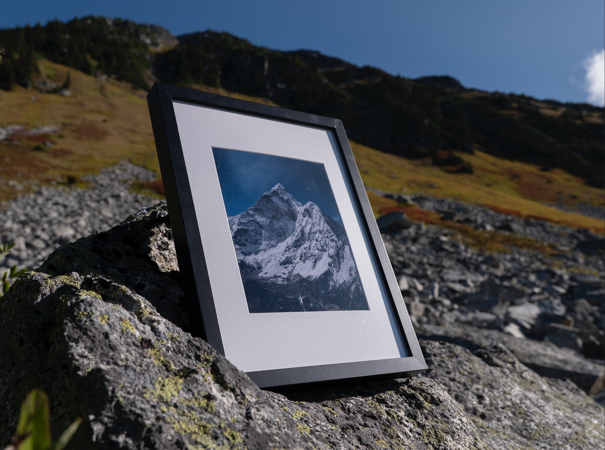 Angled view of the black-framed Solitude print on sunlit rocks.