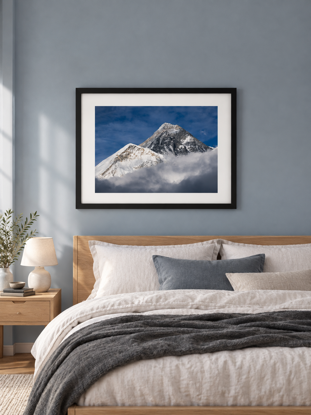 Room mockup of Emergence above a bed against a blue-gray wall.